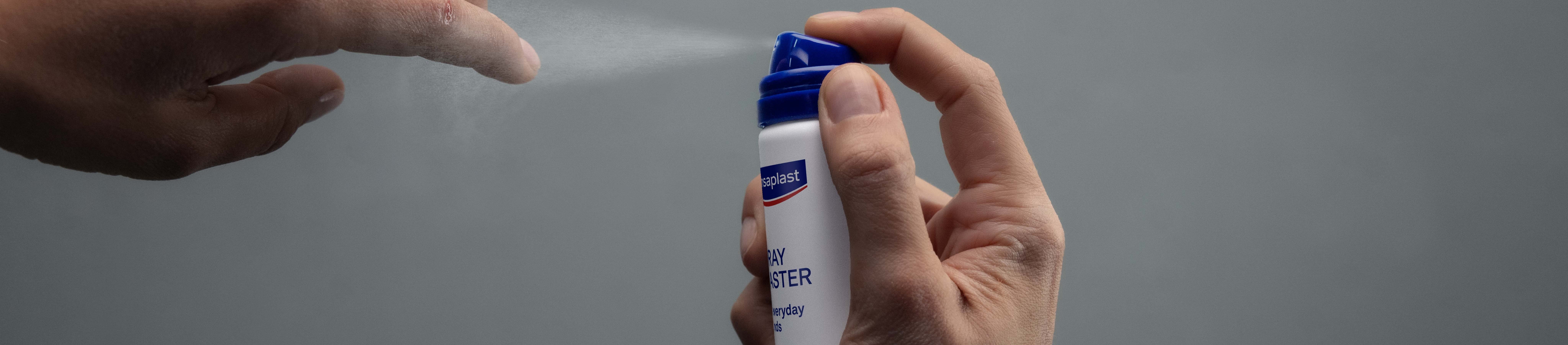 Persoon die Hansaplast Second Skin Pleisterspray op de vingertop aanbrengt