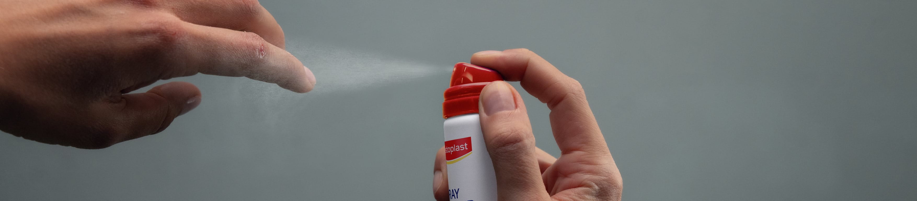 Person applying Elastoplast Second Skin Spray Plaster to their fingertip