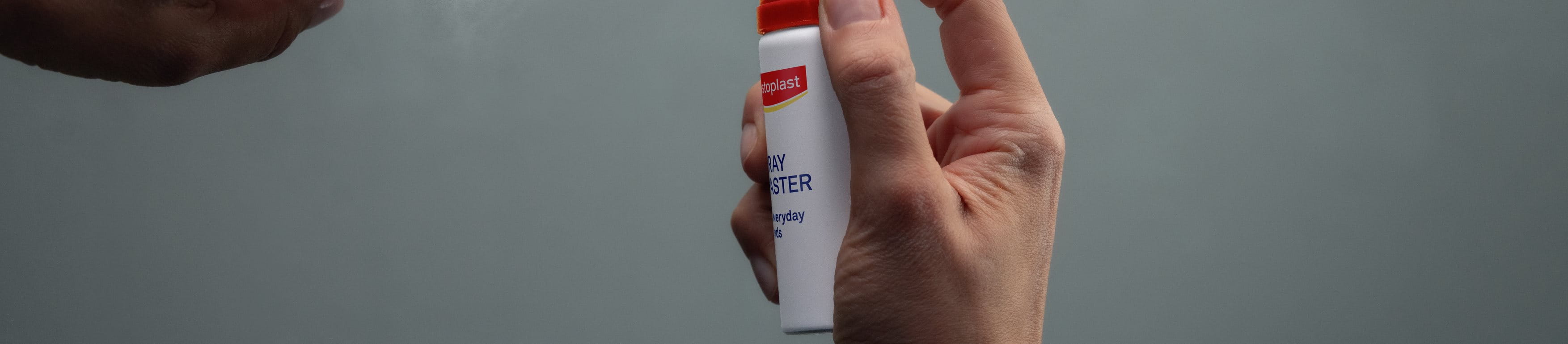 Persoon die Hansaplast Second Skin Pleisterspray op de vingertop aanbrengt