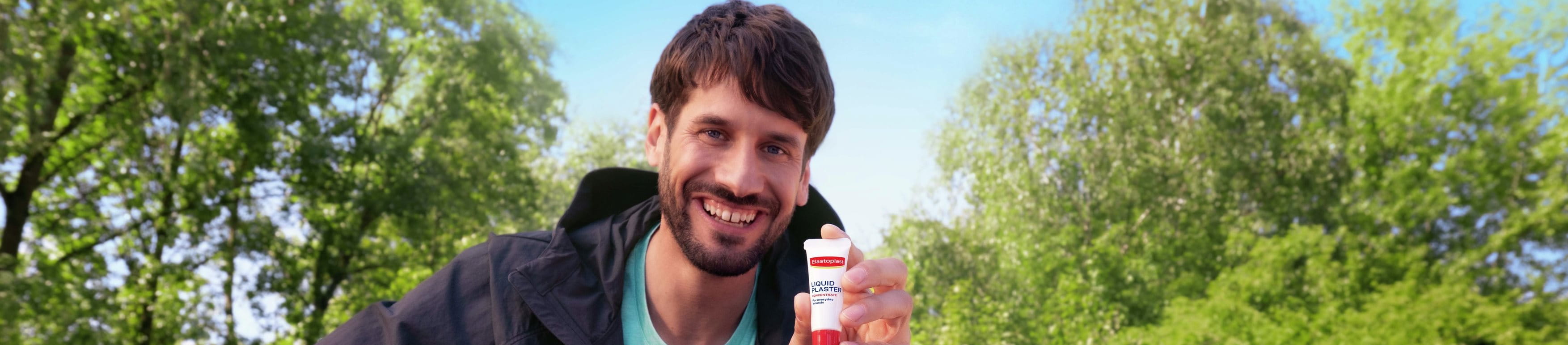 Smiling man sitting on a park bench outdoors.