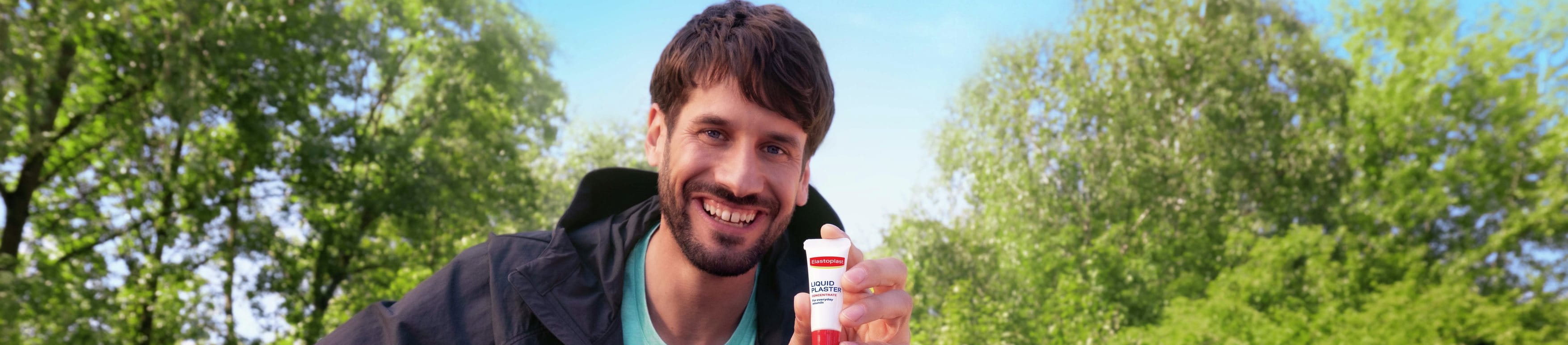 Smiling man sitting on a park bench outdoors.